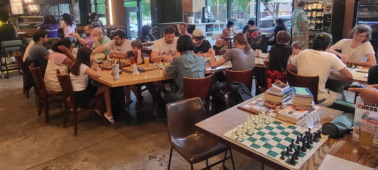People playing chess together at Durham Food Hall during a Durham Chess Club meetup.